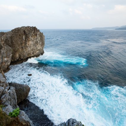 Waves crashing over rock formation cliff