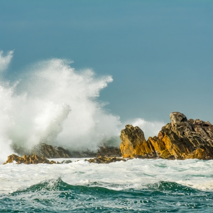 coastal rocks and splashing waves at Camps Bay in Cape Town, South Africa